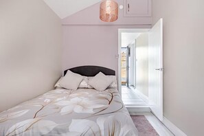Ein Schlafzimmer mit einem Bett, einer Deckenleuchte und einer Tür zu einem anderen Raum.