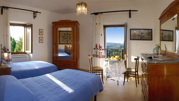 Un dormitorio con dos camas, un aparador de madera, una mesa con sillas y un ventanal con vistas.