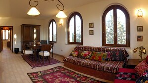 Una sala de estar acogedora con chimenea, un sofá, un comedor y ventanas grandes.
