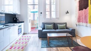 A modern apartment with a kitchen, a living area with a sofa and a coffee table, and a balcony with a view of the city. - Oasis with a sunny terrace in the heart of Gracia (Barcelona)