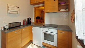 Eine kleine Küche mit Holzausstattung, einem eingebauten Backofen und einer Kaffeemaschine.