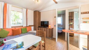 Una habitación con sofá, mesa de comedor, televisor y zona de cocina.