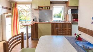 Una cocina compacta con comedor, armarios de madera y un ventanal.