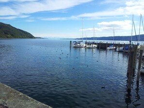 Un lac paisible où des bateaux sont amarrés à un quai, le tout étant entouré de collines.