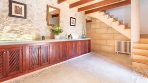 Pared de piedra, escalera de madera y un mueble de madera con un espejo.