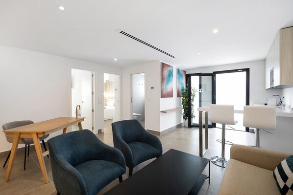 A modern living room with a sofa, a coffee table, and a dining area with a table and chairs.