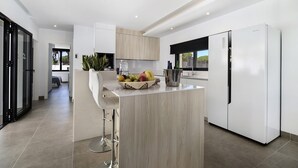 Une cuisine moderne dotée d’un îlot central, d’un réfrigérateur et d’une fenêtre.
