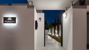 Une entrée moderne avec une enseigne indiquant « MANUELA SEA VILLA » et un chemin menant au bâtiment.
