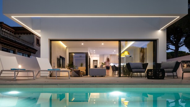 Une maison moderne avec une piscine, de grandes fenêtres et un balcon.