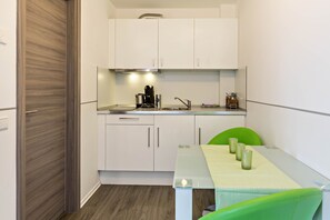 A compact kitchen with white cabinets, a stainless steel sink, and a coffee maker.