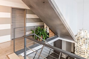 A modern staircase with metal railings, a potted plant, and a decorative light fixture.