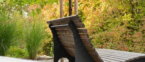 Un banc de fusta amb respatller corbat en un jardí.