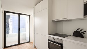 A modern kitchen with white cabinets, a black countertop, and a built-in oven. - JOIVY Spacious flat in Bairro Alto (Lisboa)