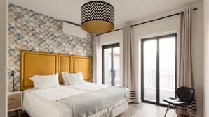 A modern hotel room with a large bed, a wooden headboard, a patterned wall, a black chair, and a large window with curtains. - JOIVY Spacious flat in Bairro Alto (Lisboa)