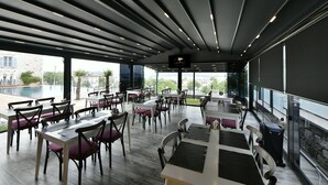A modern restaurant with a pool view, featuring a mix of table and booth seating, and a large screen for presentations. - Omer Aga Konagi (Ayvalik)