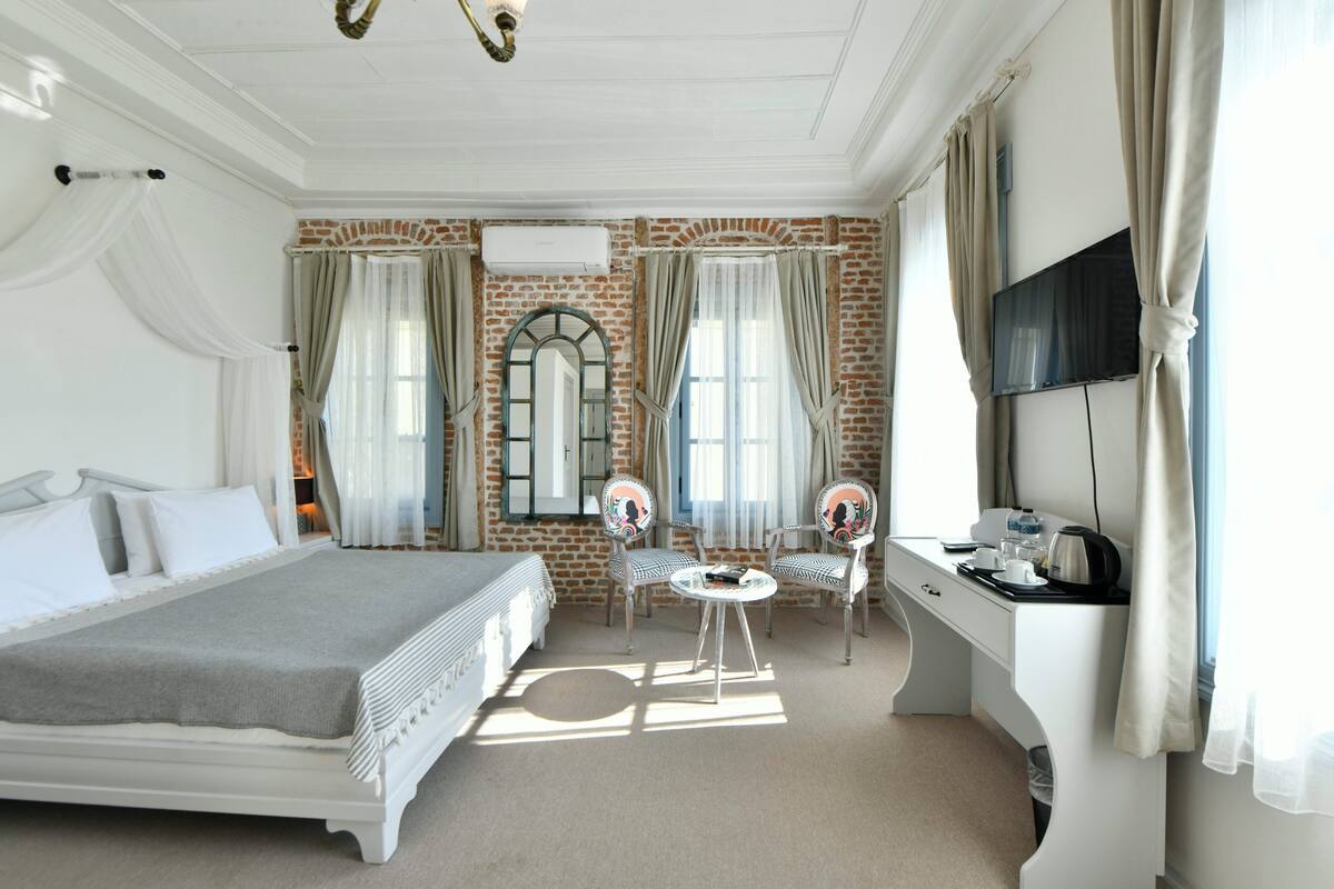 Ein Hotelzimmer mit einem großen Bett, einem Schreibtisch mit Fernseher und zwei Sesseln.