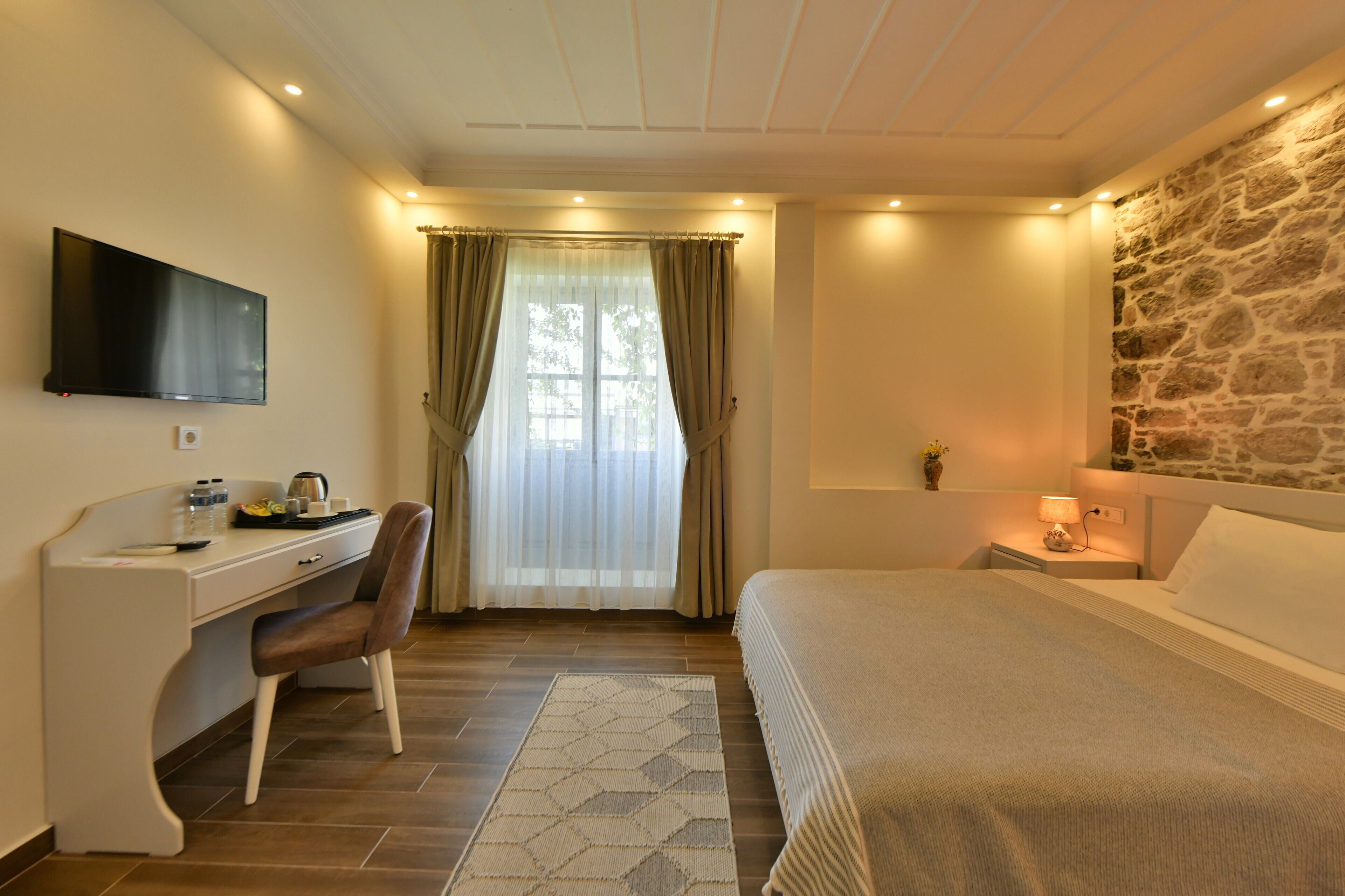 Ein Schlafzimmer mit Bett, Schreibtisch, Stuhl, Fernseher und Steinwand.