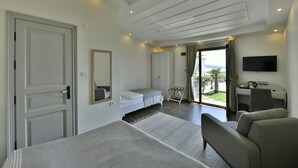 A hotel room with a bed, a sofa, a desk with a TV, and a view of the outdoors. - Omer Aga Konagi (Ayvalik)