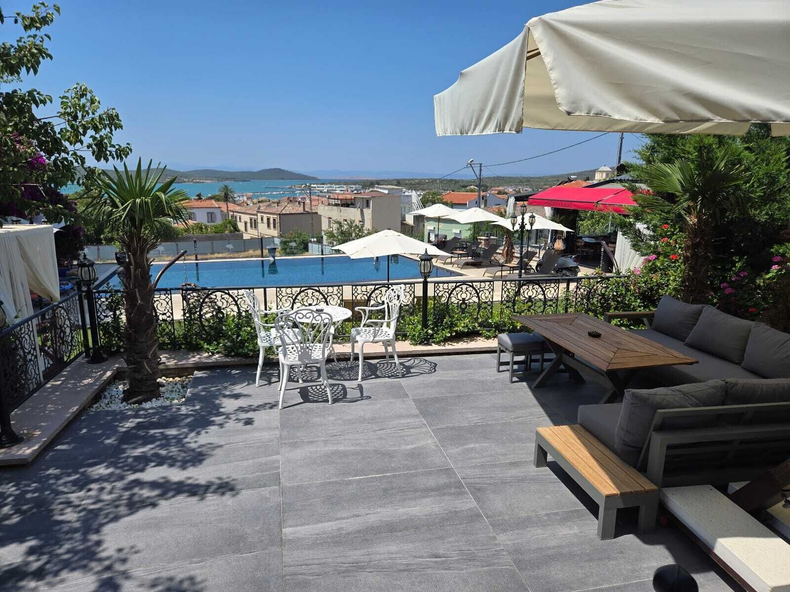 An outdoor patio with a pool, seating, and a view of the sea.
