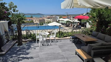 An outdoor patio with a pool, seating, and a view of the sea.