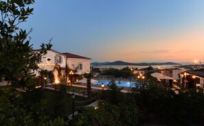 Un hotel con piscina, rodeado de vegetación y vistas al mar.