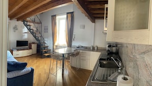 Una cocina compacta con comedor, estufa integrada y un refrigerador pequeño.