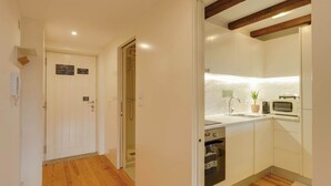 A compact kitchen with white cabinets, a microwave, and a sink. - Vitoria Duplex Apartment by DA'HOME (Porto)