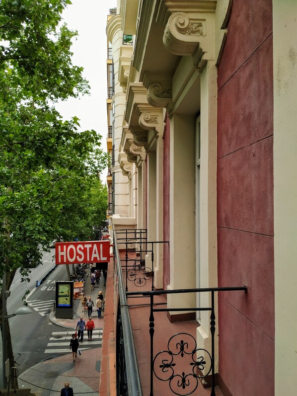 A hostel with a red sign, a pedestrian crossing, and a staircase leading to an upper floor.