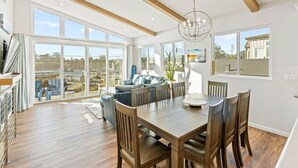 A spacious dining area with a wooden table and chairs, large windows, and a view of the outside. - Santa Cruz Harbor Vacation (Santa Cruz)