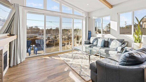 A spacious living room with a glass coffee table, leather sofas, and a large sliding glass door leading to a patio. - Santa Cruz Harbor Vacation (Santa Cruz)