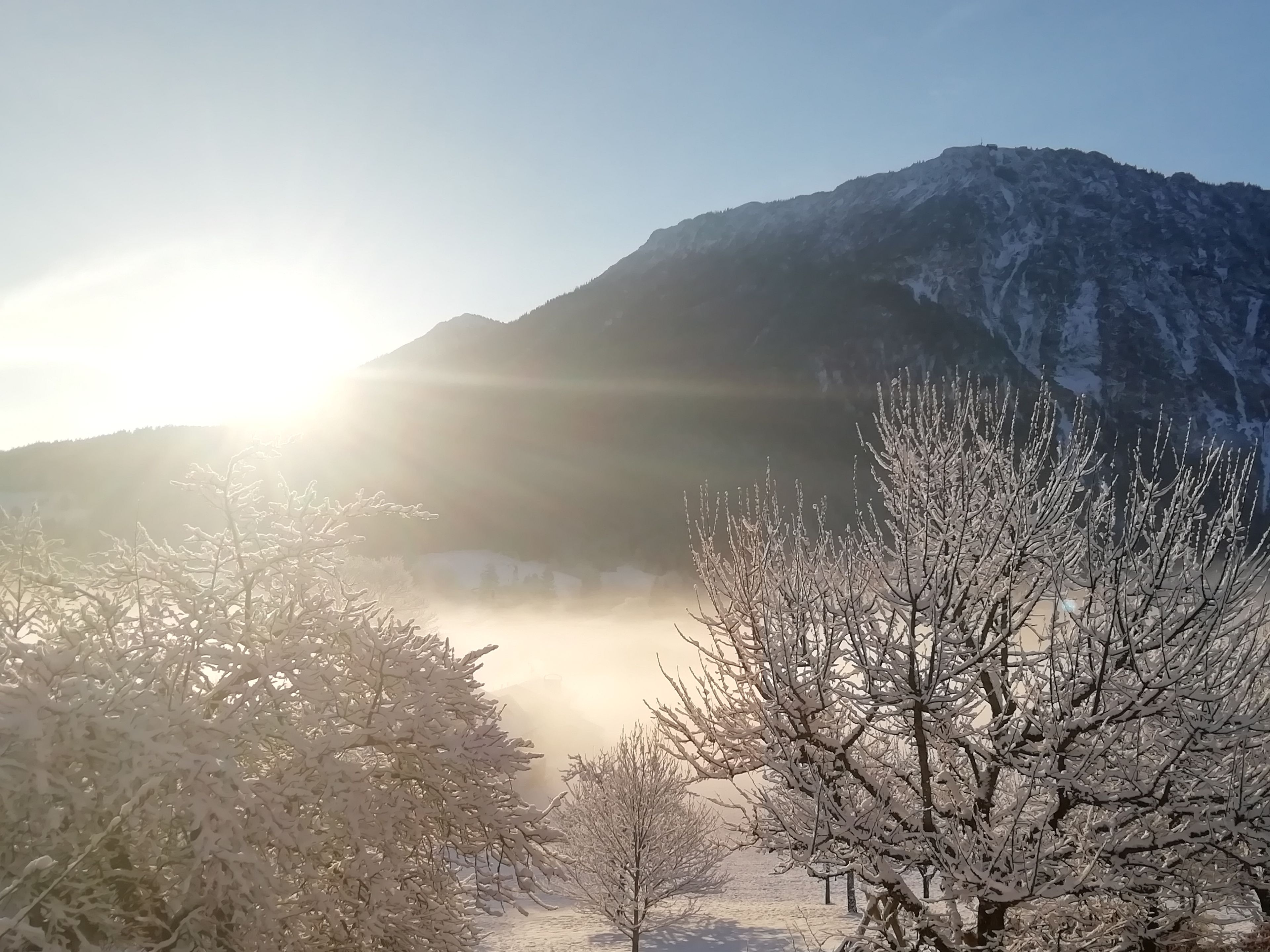 A mountainous landscape with a clear sky and sunlight.