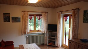 Ein gemütliches Wohnzimmer mit einem Holztisch, einem roten Sofa und einem Fernseher auf einem Regal.
