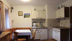 Eine kleine Küche mit Essbereich, ausgestattet mit einem Tisch, Stühlen, einer Kaffeemaschine und Schränken.