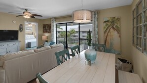 A dining area with a white table, teal chairs, and a ceiling fan.