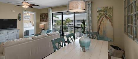 A dining area with a white table, teal chairs, and a ceiling fan.