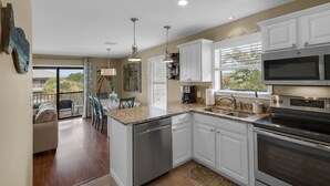A modern kitchen with white cabinets, stainless steel appliances, and a large island.