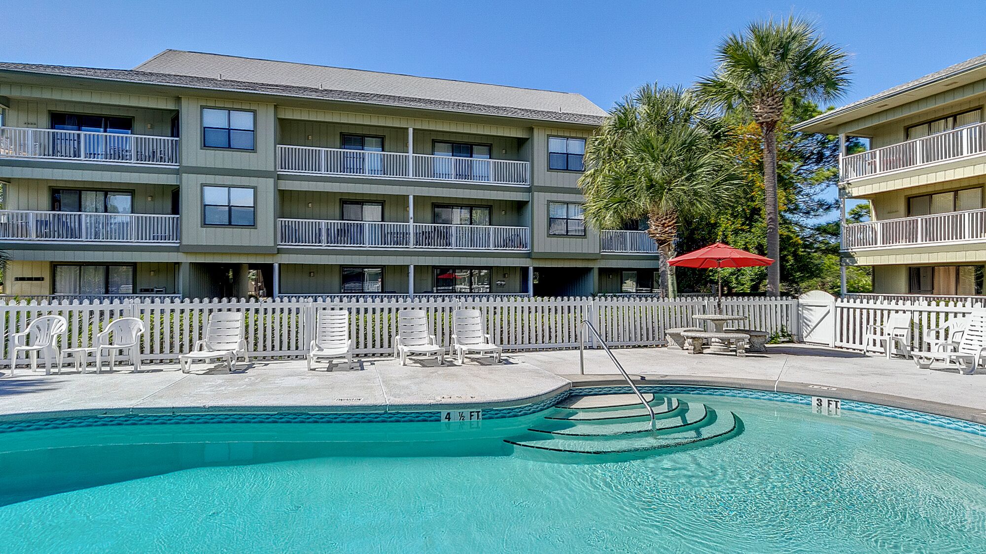 A hotel with a pool area, multiple balconies, and outdoor seating.
