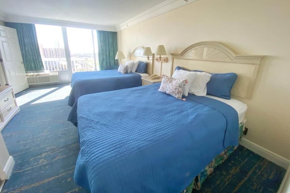 Une chambre d’hôtel avec deux lits, une grande fenêtre et une vue sur la ville.