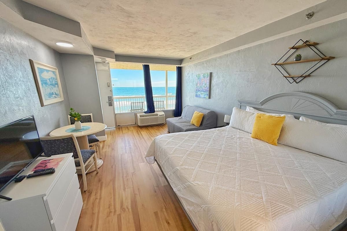Une chambre d’hôtel avec un grand lit, un petit bureau, une chaise et une vue sur l’océan.