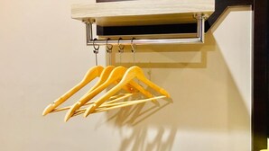 A wall-mounted wooden rack with multiple yellow hangers. - Highway Times Inn (Ipoh)