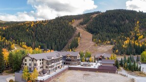 A multi-story lodge with a central courtyard, surrounded by forested hills and autumn foliage. - 2800 Slopeside 2 Bedroom Condo by RedAwning (Keystone)