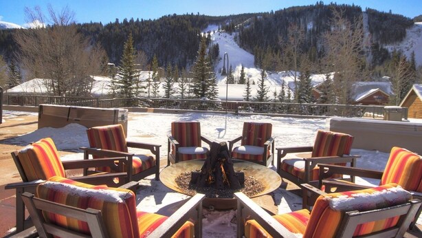 A patio area with outdoor seating and a fire pit, overlooking a snowy mountain landscape. - 2800 Slopeside 2 Bedroom Condo by RedAwning (Keystone)