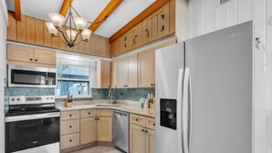 A modern kitchen with wooden cabinets, a stainless steel refrigerator, a built-in oven, and a dishwasher. - Island Gem B 2 Bedroom Villa by RedAwning (Anna Maria)