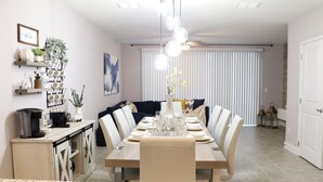 A dining area with a long table set for six, surrounded by chairs, with a decorative vase in the center. - FREE Early Check-In When Available! (Kissimmee)