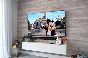 Un televisor de pantalla plana fixat a la paret amb un personatge de Disney davant d'un castell.