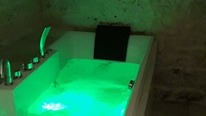 Una bañera con luz verde, un cartel arriba y una pared de piedra.