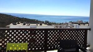 Ein Balkon mit Blick auf das Meer und Gebäude in der Ferne.