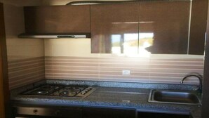 A compact kitchen with a gas stove, a sink, and dark cabinetry.