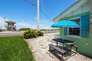 Relax and dine in a serene outdoor setting with a picnic table and umbrella, steps from the beach.