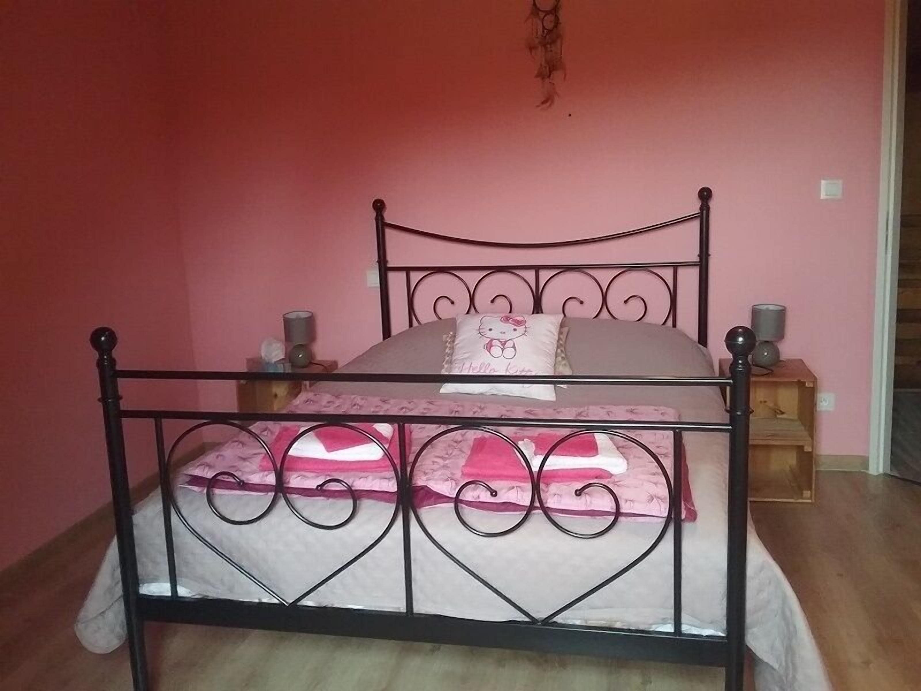 A single bed with a metal frame and a headboard, a bedside table, and a wall-mounted lamp.